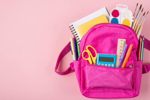 Top above overhead view photo of pink backpack and colorful stationery placed to the right side isolated on pastel pink background with copyspace - Photo, Image
