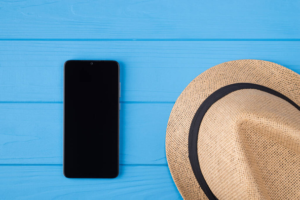Arriba arriba arriba arriba de cerca foto de sombrero femenino de paja y teléfono negro con pantalla táctil en blanco aislado sobre fondo de color brillante de madera
 - Foto, Imagen