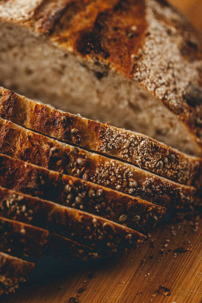 Close up view on freshly baked sourdough bread on wooden cutting board on bright backgrounda  - Foto, imagen