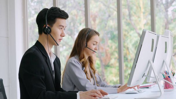Vezetékes fülhallgatót viselő üzletemberek dolgoznak az irodában, hogy támogassák a távoli ügyfelet vagy kollégát. Call center, telemarketing, ügyfélszolgálati ügynök nyújt szolgáltatást telefonon video konferencia hívás. - Fotó, kép