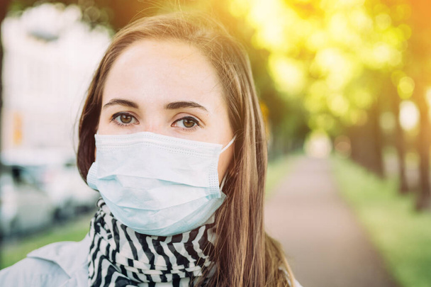 Una giovane ragazza caucasica è andata a fare una passeggiata in città indossando una maschera medica da un'infezione virale.. - Foto, immagini