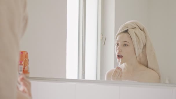 Εφηβική κοπέλα εφαρμογή lip balm και lip gloss μπροστά από τον καθρέφτη του μπάνιου - Πλάνα, βίντεο