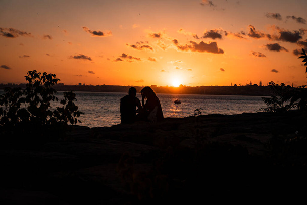 coppia romantica come silhouette benvenuti al tramonto sulle rocce che è sul mare. - Foto, immagini