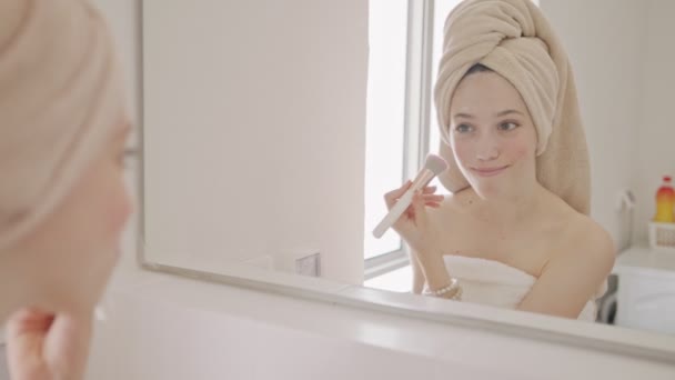 Nastolatka stosująca makijaż przed lustrem w łazience - Materiał filmowy, wideo