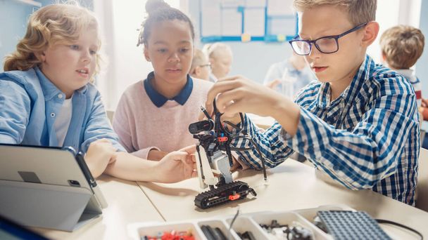 Elementary School Robotics Classroom: Diverse Group of Children Building and Programming Robot Together, Talking and Working as Team. Kids Learning Software Design and Creative Robotics Engineering - Foto, Imagem