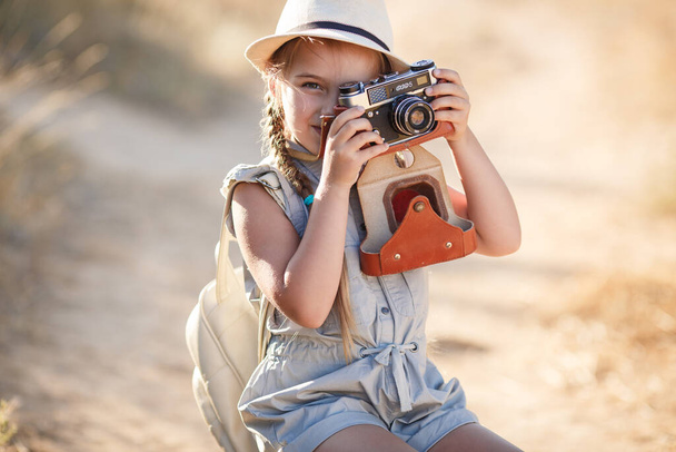 child girl traveler. trip alone. girl walking with camera and suitcase on nature by sea. travel, vacation, holidays - Фото, изображение