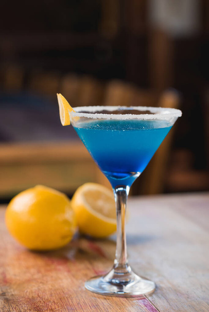 Niebieski napój koktajlowy margarita, z przodu, z cytryną w tle, na rustykalnym stole - Zdjęcie, obraz