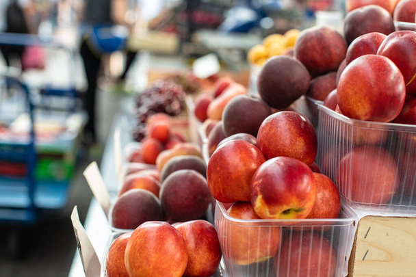 Картина солодких, смачних і свіжих персиків, що лежать в маленьких пластикових коробках в магазині
 - Фото, зображення