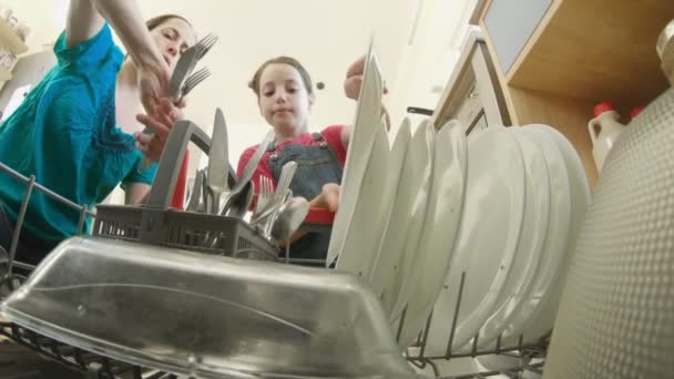 Kislány segít az anyjának megtölteni a mosogatógépet piszkos edényekkel. - Felvétel, videó