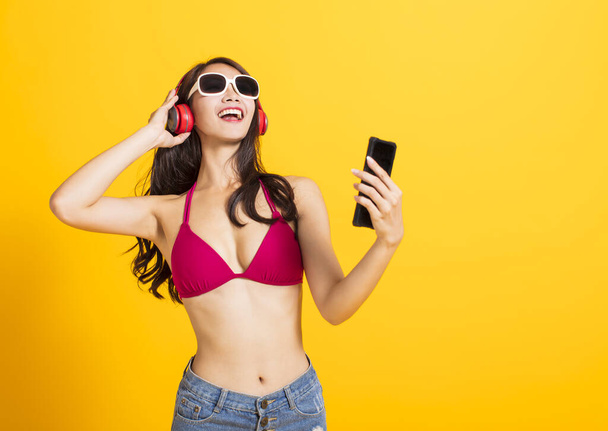 schöne junge Frau trägt Bikini im Badeanzug und schaut Smartphone  - Foto, Bild
