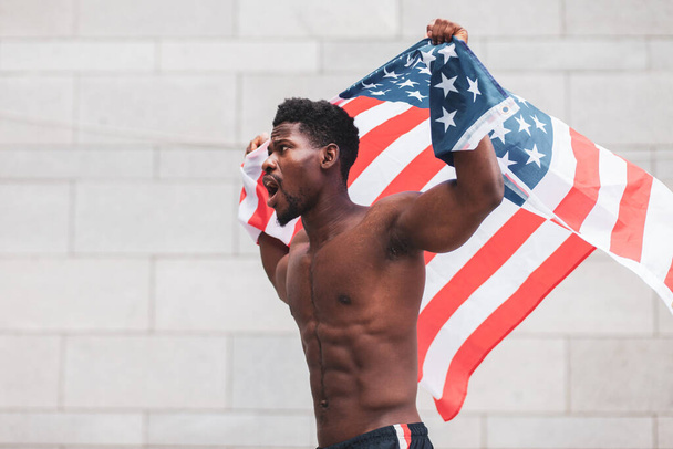 black lives matter concept. Aggressive african american guy with usa flag protests and shouts, patriot activist of america makes rebellion, copy space - Photo, Image