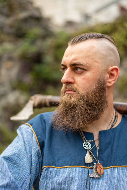 Porträt eines Wikingerkriegers mit langem Bart, Axt und Amuletten um den Hals - Foto, Bild