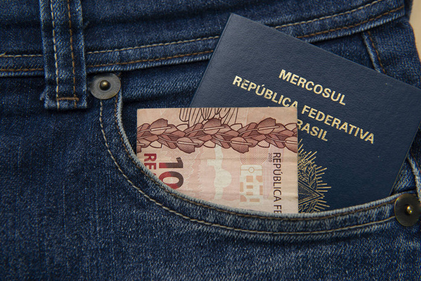 Brazilian passport in jeans pocket with Real notes. International travel and tourism concept. Business trip.Translate: Mercosur - Federative republic of Brazil. Old Blue passport. - Photo, Image