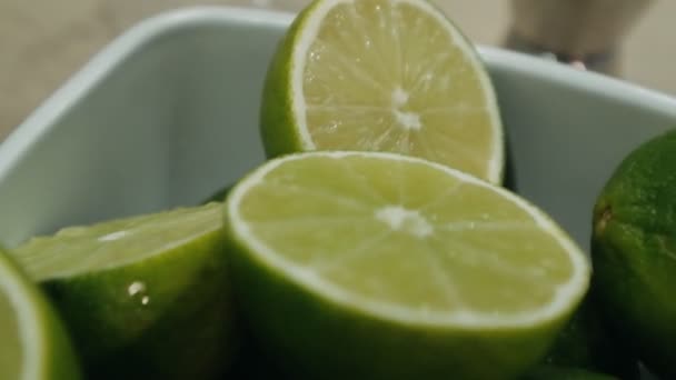 Alcoholische cocktail maken. Snijd groene limoenen in een bord op tafel - Video