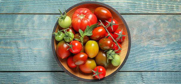 Bowl with different tomatoes on wooden table, top view. Banner design  - Фото, изображение