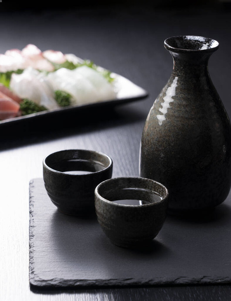 Sake e sashimi su sfondo nero - Foto, immagini