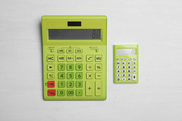 Verschiedene Taschenrechner mit den Zahlen 80 und 20 auf weißem Holzgrund, flach gelegt. Paretoprinzip-Konzept - Foto, Bild