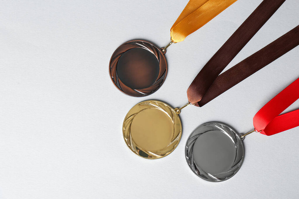 Gold, silver and bronze medals on white background, flat lay. Space for design - Foto, Imagen