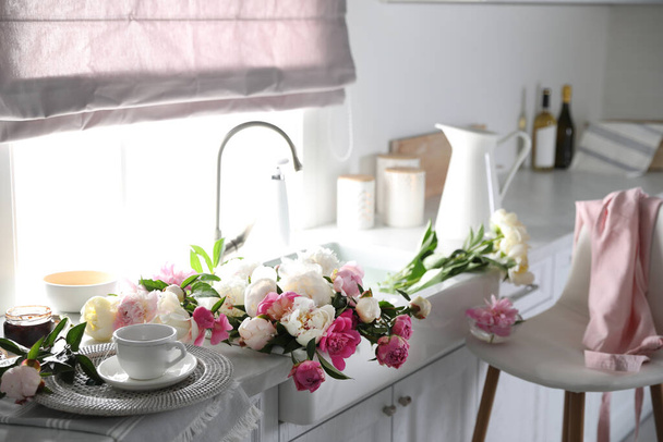 Beautiful peonies and cup of tea on kitchen counter - Foto, Imagem