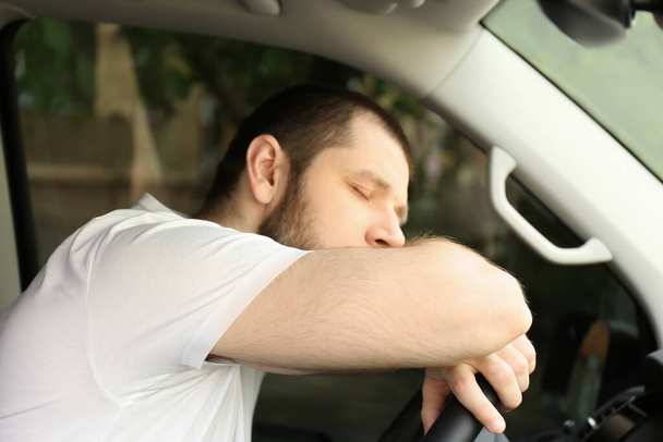 Tired man sleeping on steering wheel in his car - Foto, afbeelding