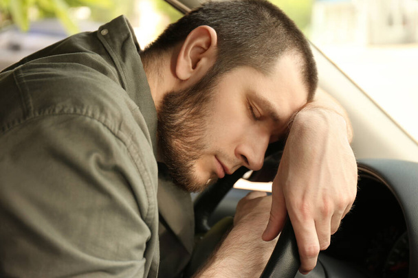 Tired man sleeping on steering wheel in his car - Photo, Image