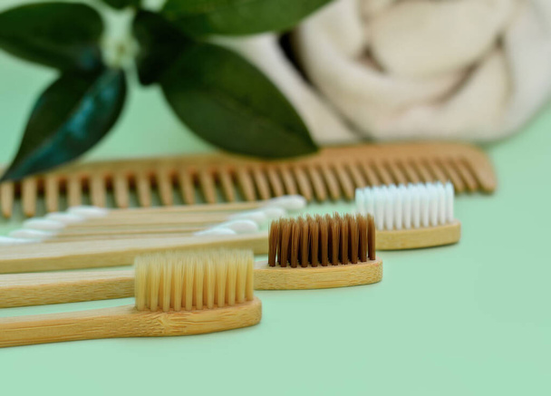 Eco natural bamboo toothbrushes on green background with greenery. Eco products plastic free. The concept of zero waste, recycling, environmental consciousness, social environmental responsibility - Photo, Image
