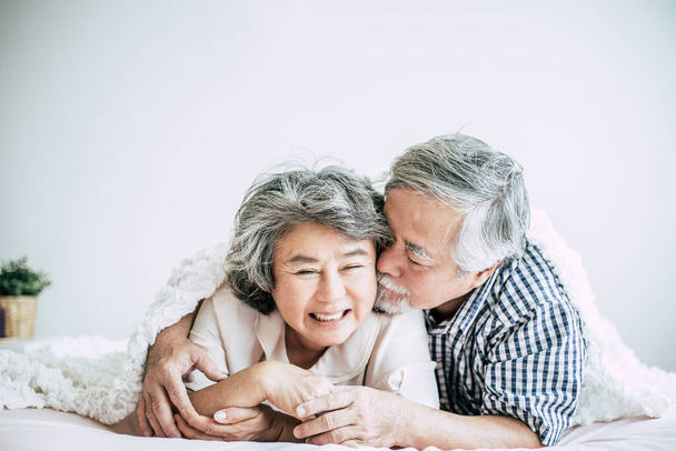 Ευτυχισμένο ζευγάρι ηλικιωμένων που γελάνε στην κρεβατοκάμαρα - Φωτογραφία, εικόνα