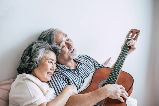 Старшие пары расслабляются, играя на акустической гитаре в спальне
 - Фото, изображение