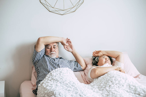 Серьезная старшая пара смотрит в сторону лежащей на кровати
  - Фото, изображение