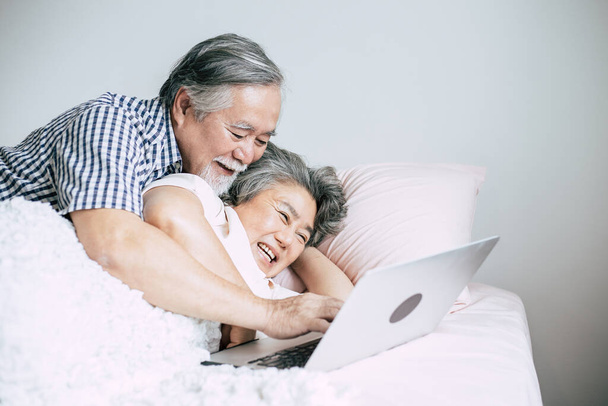 Älteres Paar benutzt Laptop im Schlafzimmer - Foto, Bild
