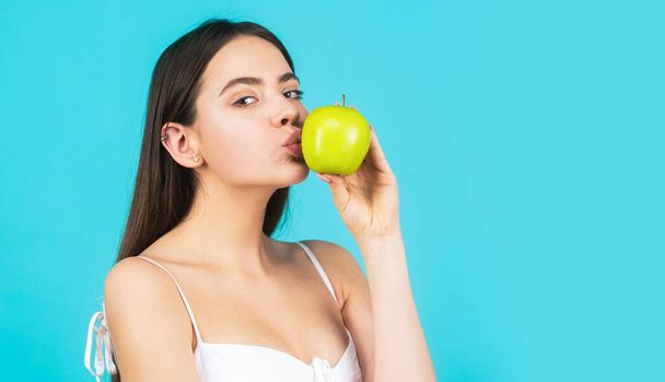 Piękna młoda kobieta jedząca jabłko. Zdrowy styl życia. Happy kobieta pocałunek jabłko na niebieskim tle - Zdjęcie, obraz