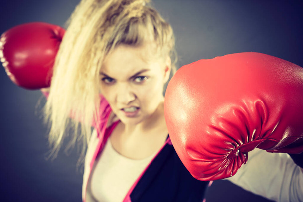 Sporty angry determined woman wearing red boxing gloves, fighting. Studio shot on dark background. - 写真・画像