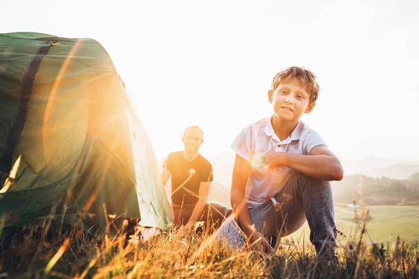 Father and son prepare for mountaing camping, set up the tent. Trekking with kids concept image - Fotografie, Obrázek