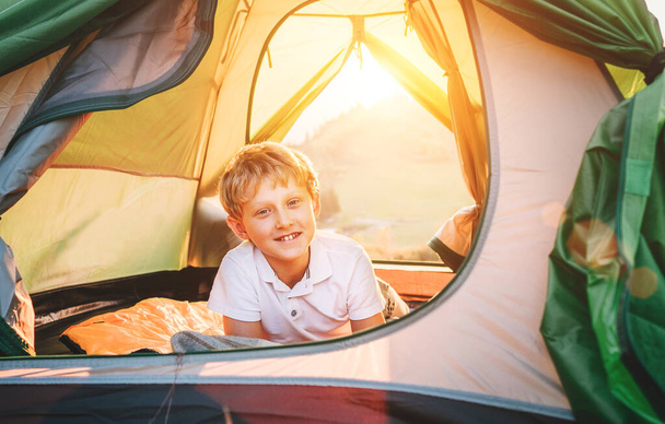 Jongen rust in campingtent. Zonsondergang in de natuur - Foto, afbeelding