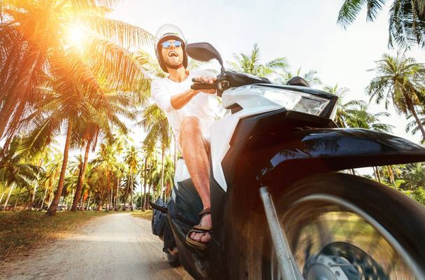 Man riding motorbike under palm trees - Valokuva, kuva