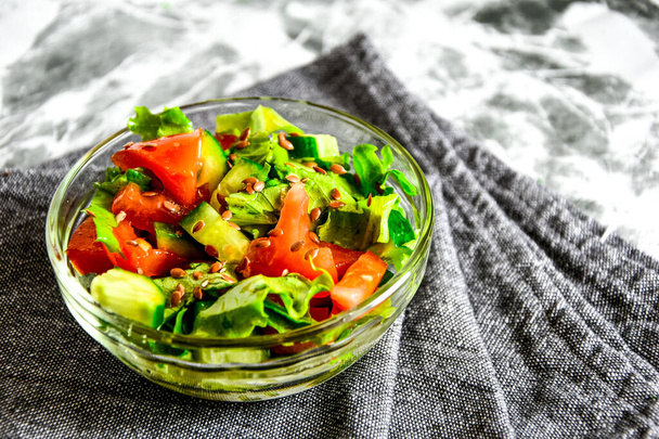 Schüssel mit frischem Salat mit Tomaten, Gurken, Salat, Leinsamen, vegetarischem Essen, gesunder Ernährung, Ernährungskonzept. Veganes Essen - Foto, Bild