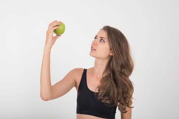 Mujer de belleza sosteniendo manzana verde mientras está aislada en blanco
 - Foto, imagen