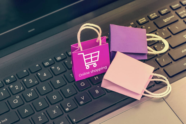 Online winkelen, e-commerce concept: papieren boodschappentassen op notebooktoetsenbord. toont aankoop van producten en diensten op het internet kan kopen goederen of diensten in het buitenland. - Foto, afbeelding