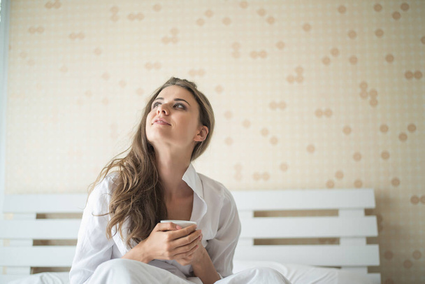 Beautiful woman at her bedroom drinking coffee in the morning - Фото, зображення
