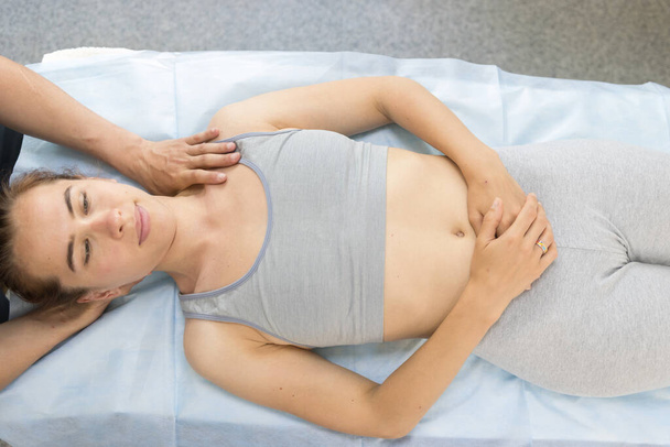 Молодая женщина, проходящая хиропрактическое лечение - лежит на диване, а врач держит ее голову и давит на плечо
 - Фото, изображение