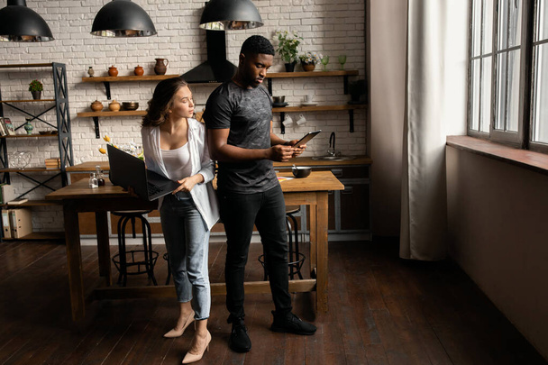 Young couple  with laptop and tablet  on kitchen  - Photo, image