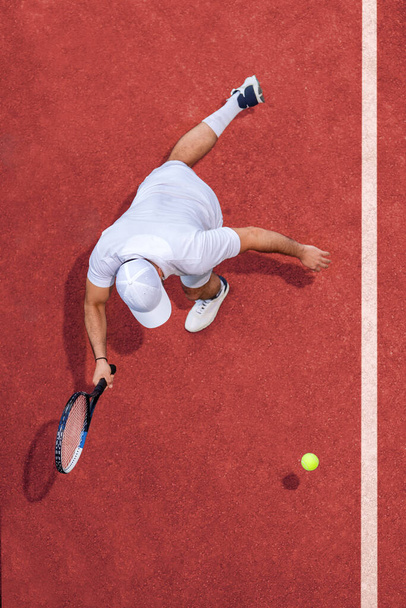 男性テニスプレーヤーのトップビューボールを打つラケット. - 写真・画像