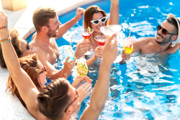 Group of friends having party in pool, drinking cocktails  and enjoying together. - Фото, зображення