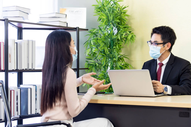 Portrait of Asian business advisor giving advice to customer about financial loan situation in bank office. New normal social distance business for banking financial and investment concept. - Photo, Image