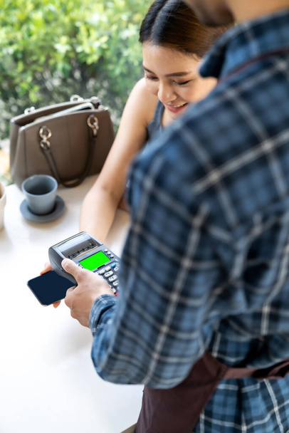 Asian woman customer moblie phone to make online contactless mobile payment after eating out in new normal social distance restaurant. Online contactless and technology concept. - 写真・画像