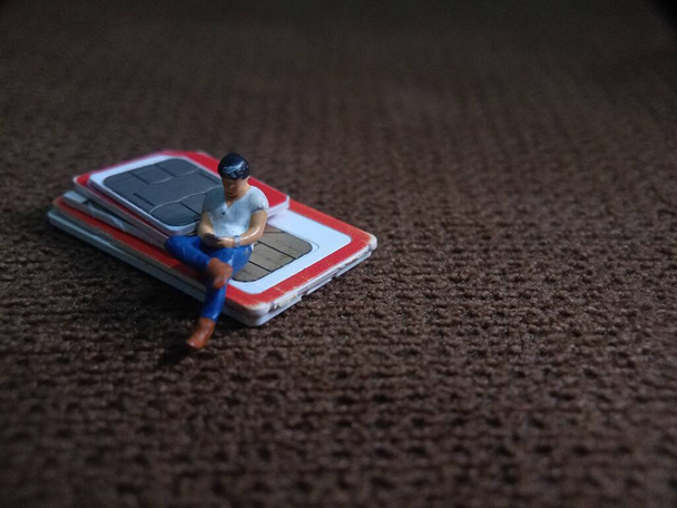 Homem sentado segurando Smartphone no cartão SIM, ilustração para tecnologia de comunicação Artigo relacionado
 - Foto, Imagem