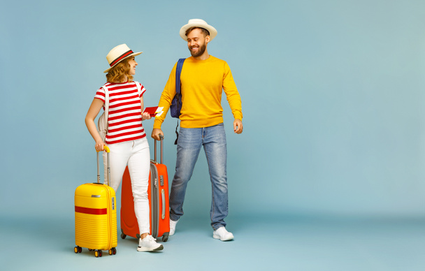 Koko kehon onnellinen pari iloinen parrakas mies hymyilee tyttöystävä matkatavarat ja liput kesälomalla vastaan sininen backdro - Valokuva, kuva