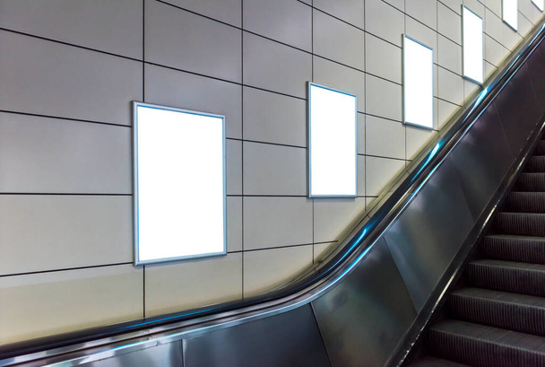 地下鉄駅での空のポスターのモックアップ。地下鉄エスカレーターの背景を持つ4つの大きな垂直、肖像画の向きの空白のポスター. - 写真・画像