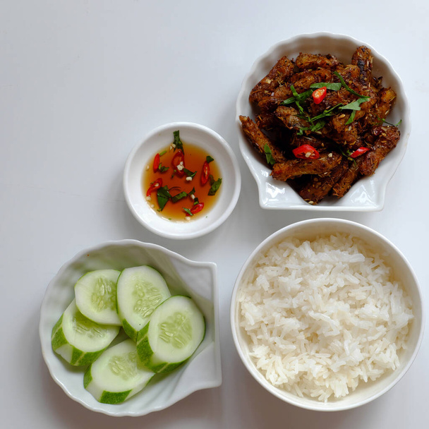 Top view tarjotin vietnamilaisen aterian lounaaksi valkoisella taustalla, kasvissyöjä kotitekoista ruokaa seitan paistettu sitronella, chili, kulhoon kasviskeittoa ja riisiruokia, yksinkertainen keittiö kasviksista - Valokuva, kuva
