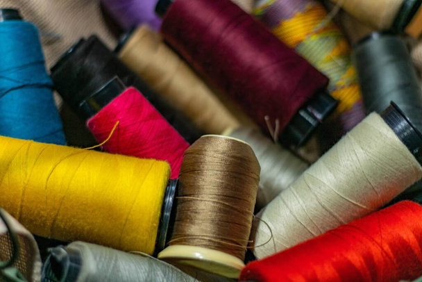 Πολλά πολύχρωμα νήματα ρολά σε ένα υφαντό καλάθι στο στούντιο ενός ράφτη - Φωτογραφία, εικόνα
